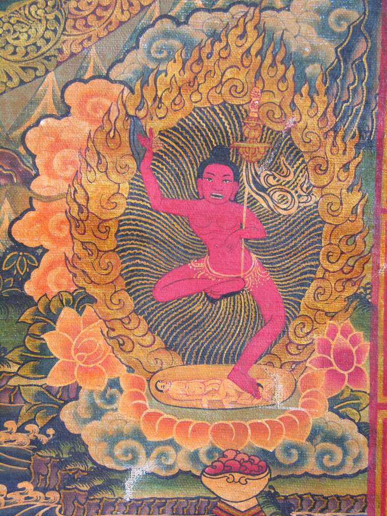Chakrasamvara Mandala 06 Bottom Right - Vajrayogini Below the mandala on the right is Vajrayogini, the dakini of wisdom. She carries a knife in her right hand and a bone khatvanga with her left arm. The Yogini's nudity demonstrates her freedom from ordinary conceptions and appearances, which bind us ordinary mortals.